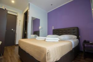 a bedroom with purple walls and a bed with white pillows at Cosmopolit in Athens