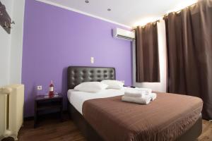 a bedroom with purple walls and a bed with towels on it at Cosmopolit in Athens