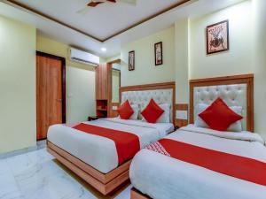 two beds in a hotel room with red pillows at Sarthak Palace - Near New delhi Railwey station in New Delhi