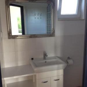 a white bathroom with a sink and a mirror at Białe domki in Jastrzębia Góra