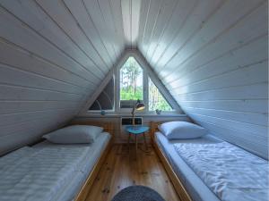 2 Betten in einem kleinen Zimmer mit Fenster in der Unterkunft Ferienhaus Finn im Heidpark Silz in Silz