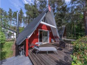 ein rotes Haus mit einem schwarzen Dach auf einer Terrasse in der Unterkunft Ferienhaus Finn im Heidpark Silz in Silz