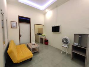 sala de estar con sofá amarillo y TV en De Hanami Homestay, en Cirebon