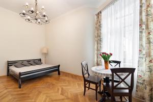 1 dormitorio con 1 cama, mesa y sillas en Apartments WHITE HOUSE, en Leópolis