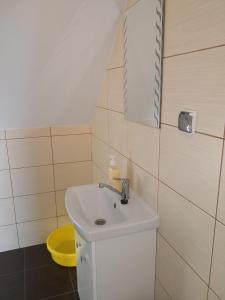 a bathroom with a white sink and a yellow bucket at Apartament bocian in Kruklanki