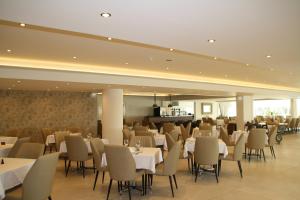 a dining room with white tables and chairs at Queens Bay Hotel in Paphos