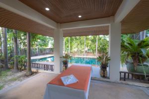 a screened in porch with a table and a pool at Blue Beach Grand Resort And Spa in Rawai Beach