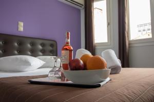 a bowl of fruit and a bottle of wine on a bed at Cosmopolit in Athens