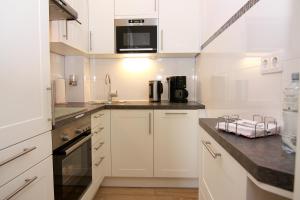 a white kitchen with a sink and a microwave at Ferienwohnung Marina Wendtorf App. 6110 in Wendtorf