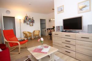 ein Wohnzimmer mit einem TV und einem Tisch in der Unterkunft Ferienwohnung Marina Wendtorf App. 6110 in Wendtorf