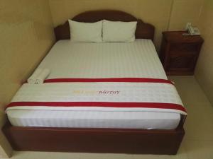 a bed with a wooden headboard and white sheets at Bao Thy Motel in Chau Doc
