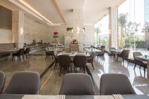 a restaurant with tables and chairs and large windows at Elegant Airport Hotel in Bangkok