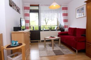 ein Wohnzimmer mit einem roten Sofa und einem Fenster in der Unterkunft Ferienwohnung Ostsee App. 6111 in Wendtorf
