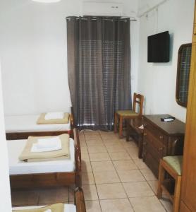 a room with two beds and a desk and a television at The Village in Igoumenitsa