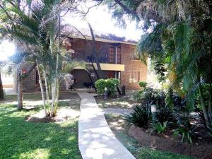 a house with palm trees in front of a building at Lepha Guest House in Onverwacht