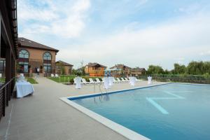 a swimming pool with white chairs and a building at WISH Aqua&SPA Resort in Vishenki