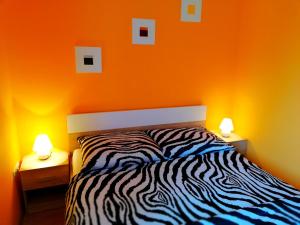 1 dormitorio con paredes de color naranja y 1 cama con 2 lámparas en Balaton Beach Apartman, en Siófok