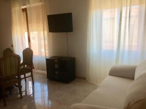 a living room with a couch and a tv on the wall at A Due Passi in La Maddalena
