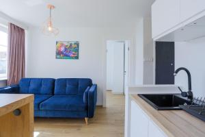 ein Wohnzimmer mit einem blauen Sofa und einer Küche in der Unterkunft Apartament IGO OLD TOWN in Danzig
