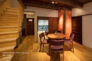 a dining room with a table and chairs and a staircase at THE MACHIYA VILLA Sanjo Shirakawa Koji in Kyoto