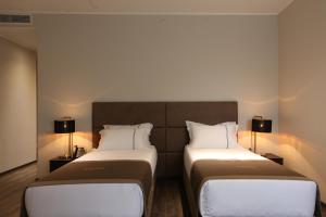 two beds in a hotel room with two lamps at LETO Boutique Hotel Zugdidi in Zugdidi