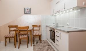 una cucina con tavolo, sedie e lavandino di Valentina Apartman a Petrovac na Moru