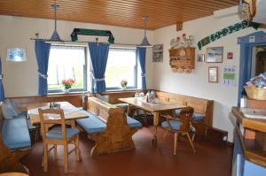 ein Restaurant mit Holztischen, Stühlen und Fenstern in der Unterkunft Gasthof Tauernalm in Heiligenblut