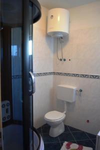 a bathroom with a toilet and a light on the wall at Apartmani Anđela in Vinišće