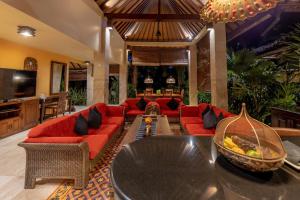una sala de estar con sofás rojos y una mesa. en Bidadari Private Villas & Retreat, en Ubud