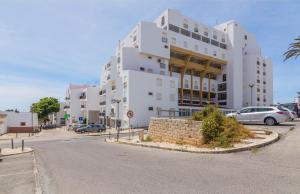 a white building with cars parked in a parking lot at H&H seaview in Luz