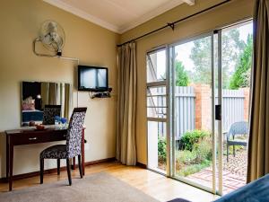a living room with a desk and a sliding glass door at Brahman Hills - Gardens, Hotel & Cottages in Nottingham Road
