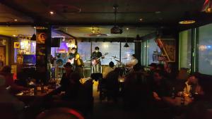 a group of people sitting in a bar with a band at Gangneung Guesthouse Myu in Gangneung