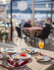 una mesa con platos de comida y un vaso de zumo de naranja en Seafront rooms Koluna en Komiža