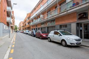 een rij auto's geparkeerd aan de kant van een straat bij Apartamentos Cornellalux in Cornellà de Llobregat