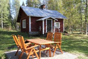 Koli Freetime Cottages في Ahmovaara: طاولة نزهة وكراسي أمام كابينة