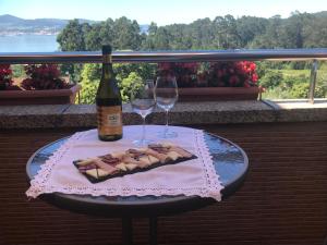 een tafel met twee glazen en een fles wijn bij Loira ático con vistas al mar in Poio