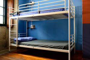 2 łóżka piętrowe w pokoju z niebieską ścianą w obiekcie Albergue O Fogar de Teodomiro w Santiago de Compostela