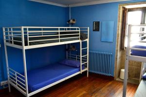 2 łóżka piętrowe w pokoju z niebieskimi ścianami w obiekcie Albergue O Fogar de Teodomiro w Santiago de Compostela