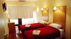 duas camas num quarto de hotel com lençóis vermelhos em Juramento de Lealtad Townhouse Hotel em Buenos Aires