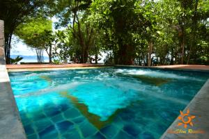a swimming pool with blue water and trees in the background at Sunshine Residence in Baan Tai