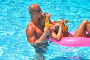 
a man sitting in a pool of water while holding a hot dog at Heronissos Hotel in Hersonissos
