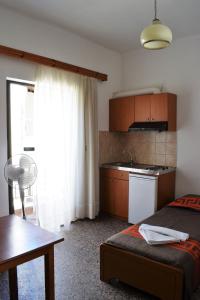 a bedroom with a bed and a kitchen with a window at Esperia Home Style Pension in Malia