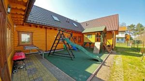 a house with a playground with a swing at Domki AGA in Mrzeżyno