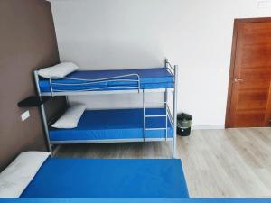 Zimmer mit 2 Etagenbetten und einem blauen Bett in der Unterkunft Albergue Mar de Rostro in Kap Finisterre