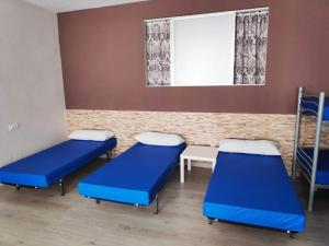 um quarto de hospital com camas azuis e uma janela em Albergue Mar de Rostro em Finisterre