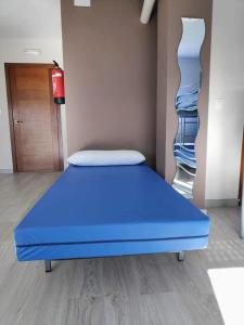 Cama azul en habitación con armario en Albergue Mar de Rostro en Finisterre