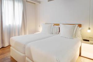 a white bedroom with a large white bed with white pillows at One Shot Prado 23 in Madrid