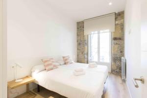 Un dormitorio blanco con una cama grande y una ventana en The Rentals Collection - Buen Pastor I, en San Sebastián