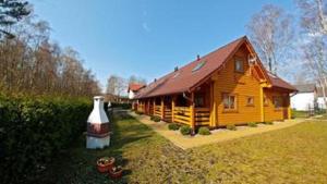 una casa de madera con un jarrón grande delante de ella en Domki AGA en Mrzeżyno