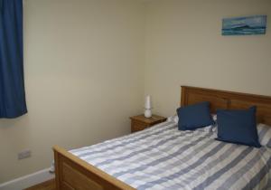 1 dormitorio con 1 cama con 2 almohadas azules en Callie's Cottage, en North Berwick